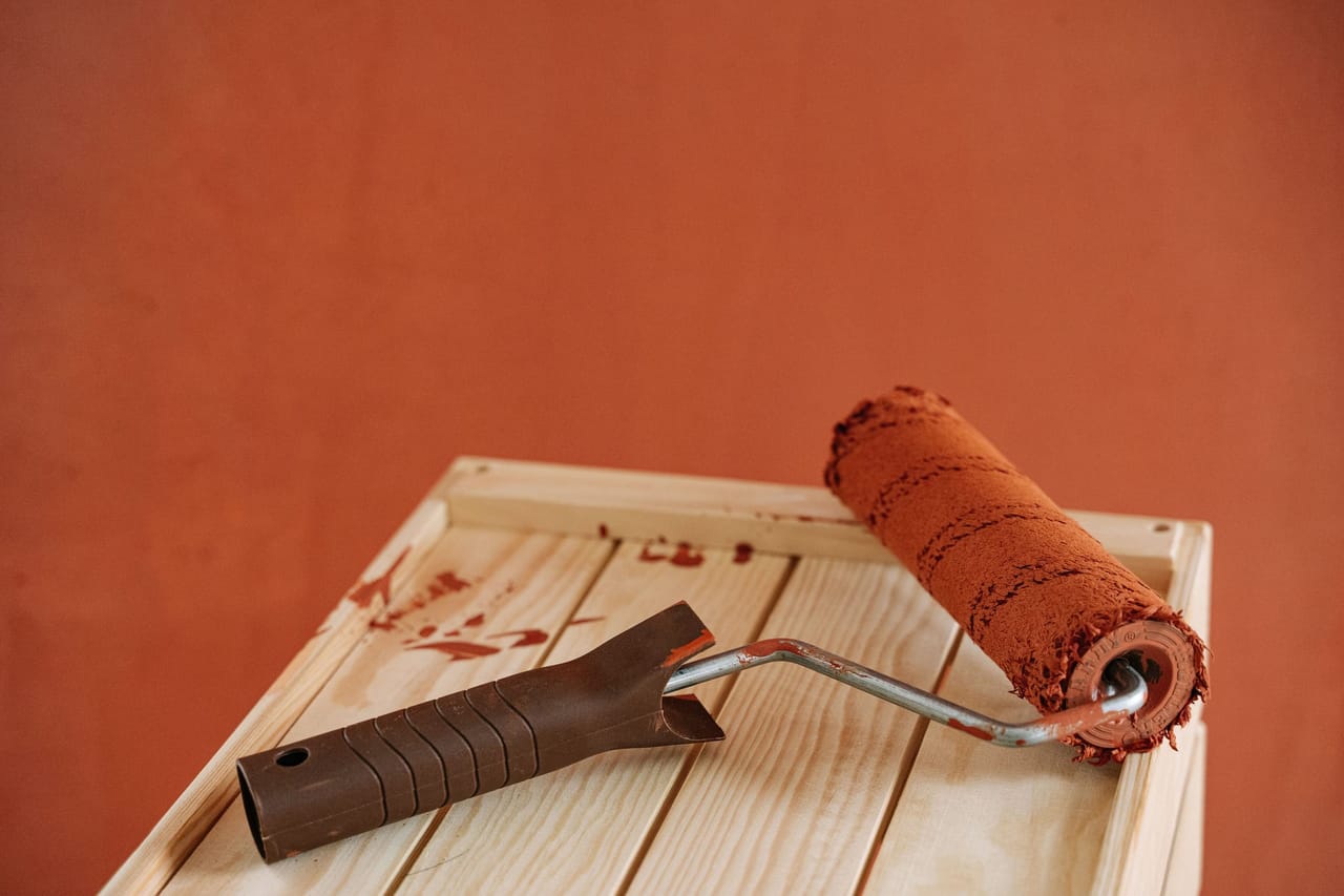 Rouleau chargé de saturateur brun sur une planche de bois