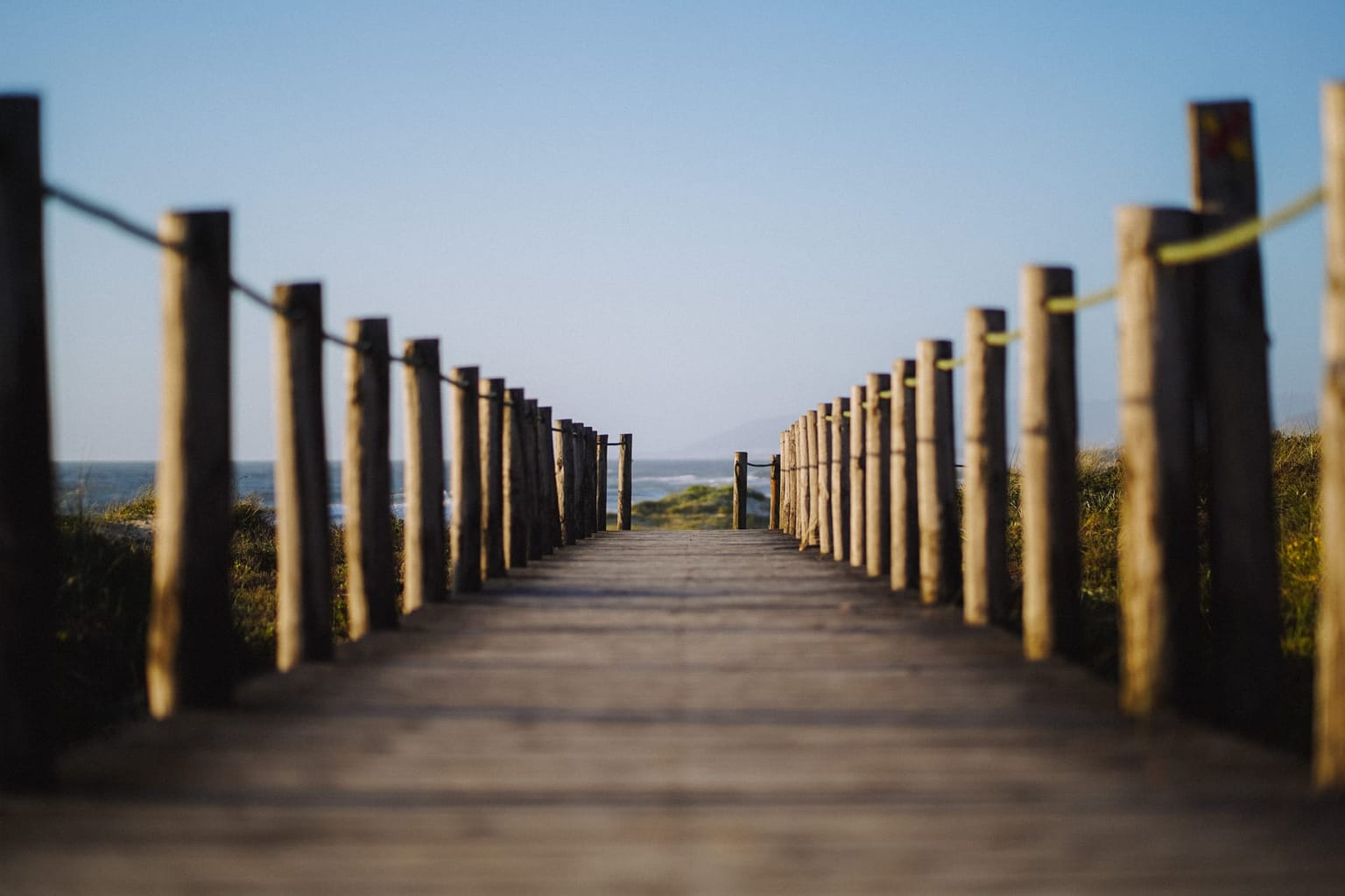 Platelage bois menant à la plage entre deux rangées de pieux