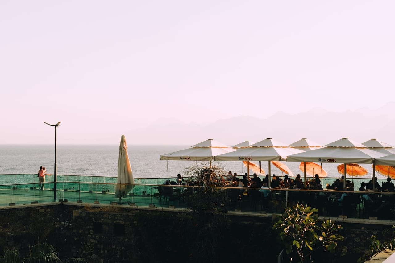 Terrasse ombragée par une rangée de parasols en fin de journée