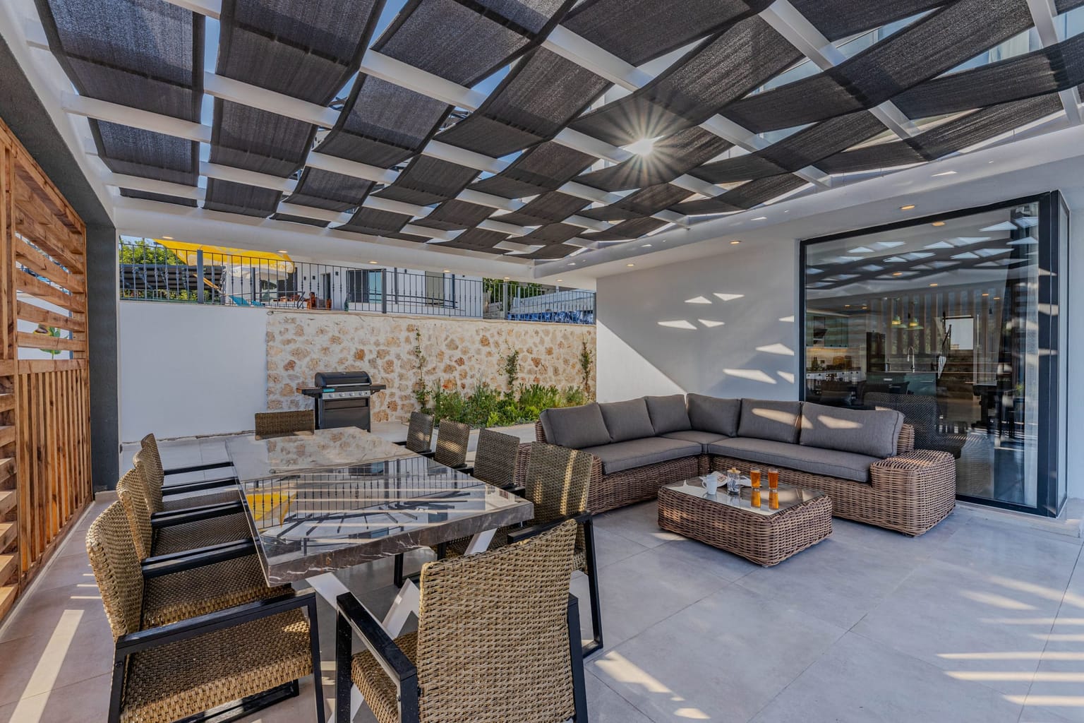 Salon de jardin installé sous une couverture de pergola à lames