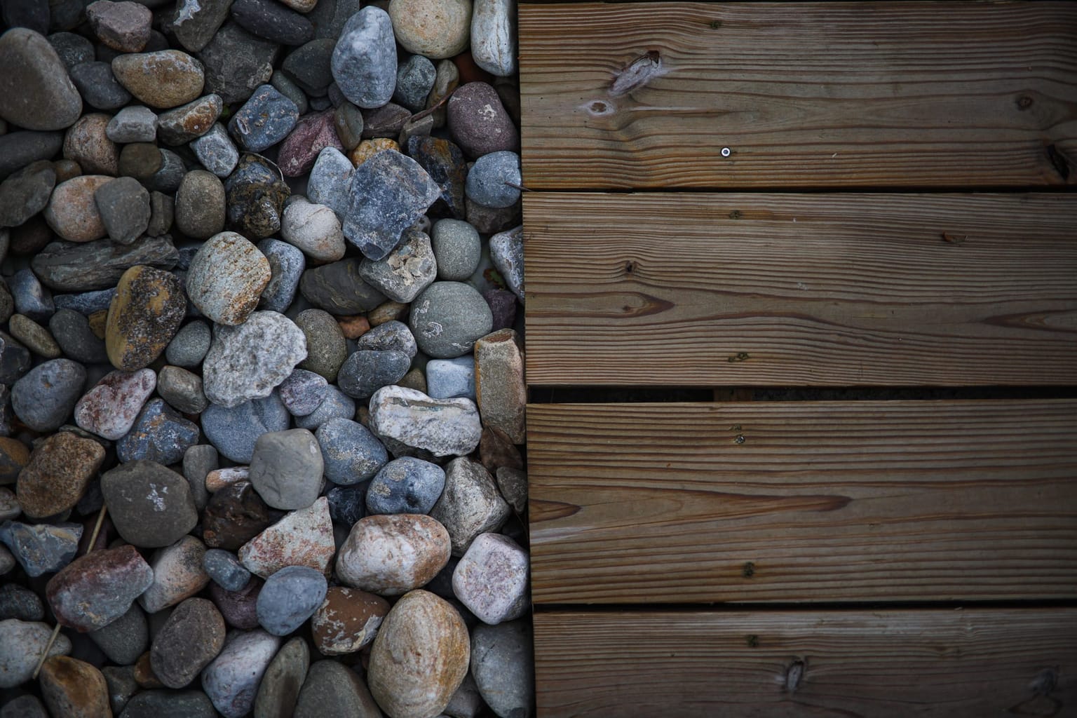 Lit de galets bordant les lames d'une terrasse bois, vu du dessus