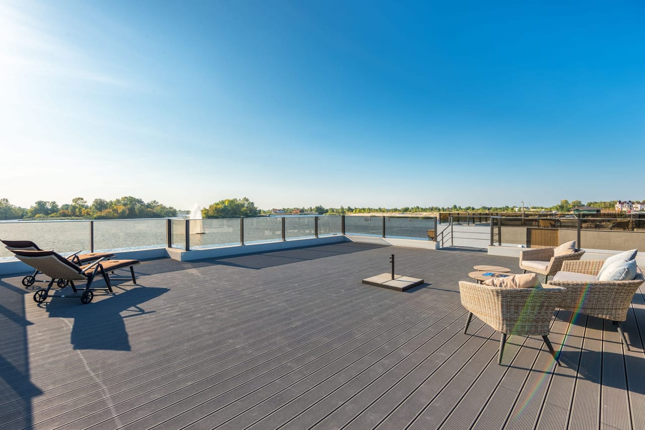 Grande terrasse aux lames uniformes au bord de l'eau, avec salon d'extérieur