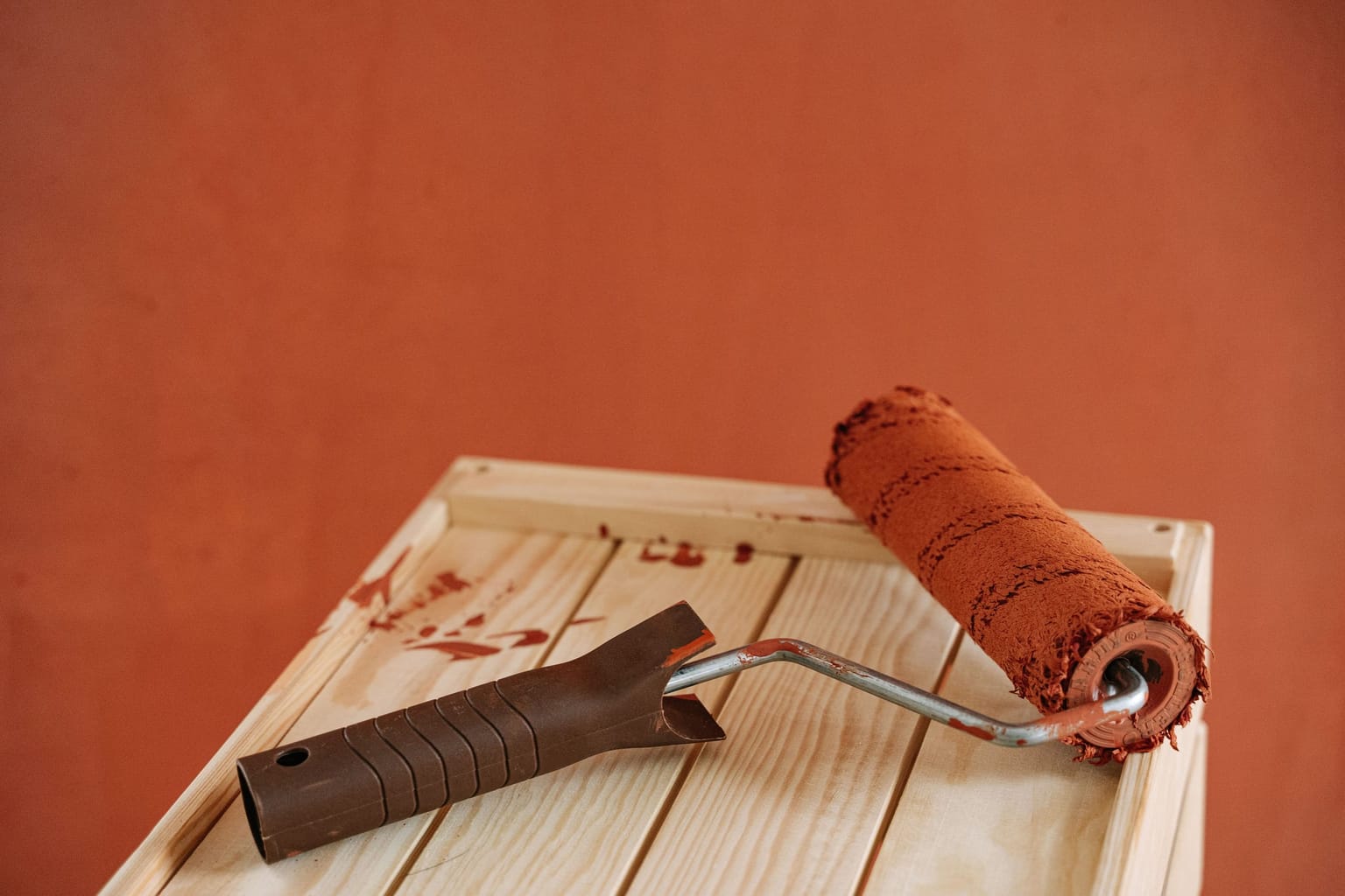Rouleau chargé de saturateur brun sur une planche de bois