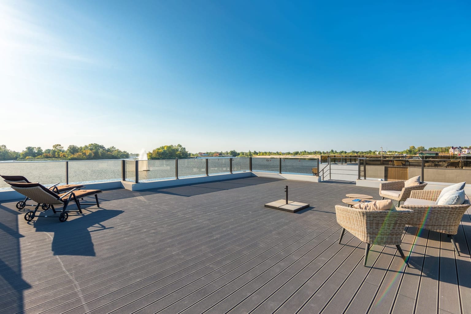 Grande terrasse aux lames uniformes au bord de l'eau, avec salon d'extérieur