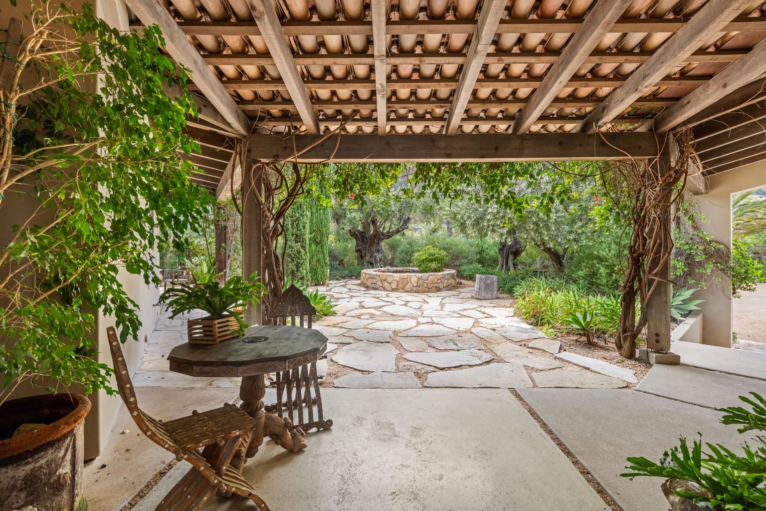 Salon d'extérieur en bois abrité sous une pergola végétalisée